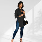 woman wearing a black oversized shirt dress facing forward showcasing the fit and style.