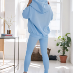 woman wearing a black snap fit hoodie with gray leggings facing backward showcasing the fit and style.