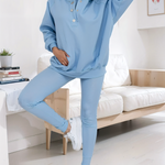 woman wearing a blue snap fit hoodie with blue leggings facing forward showcasing the fit and style.